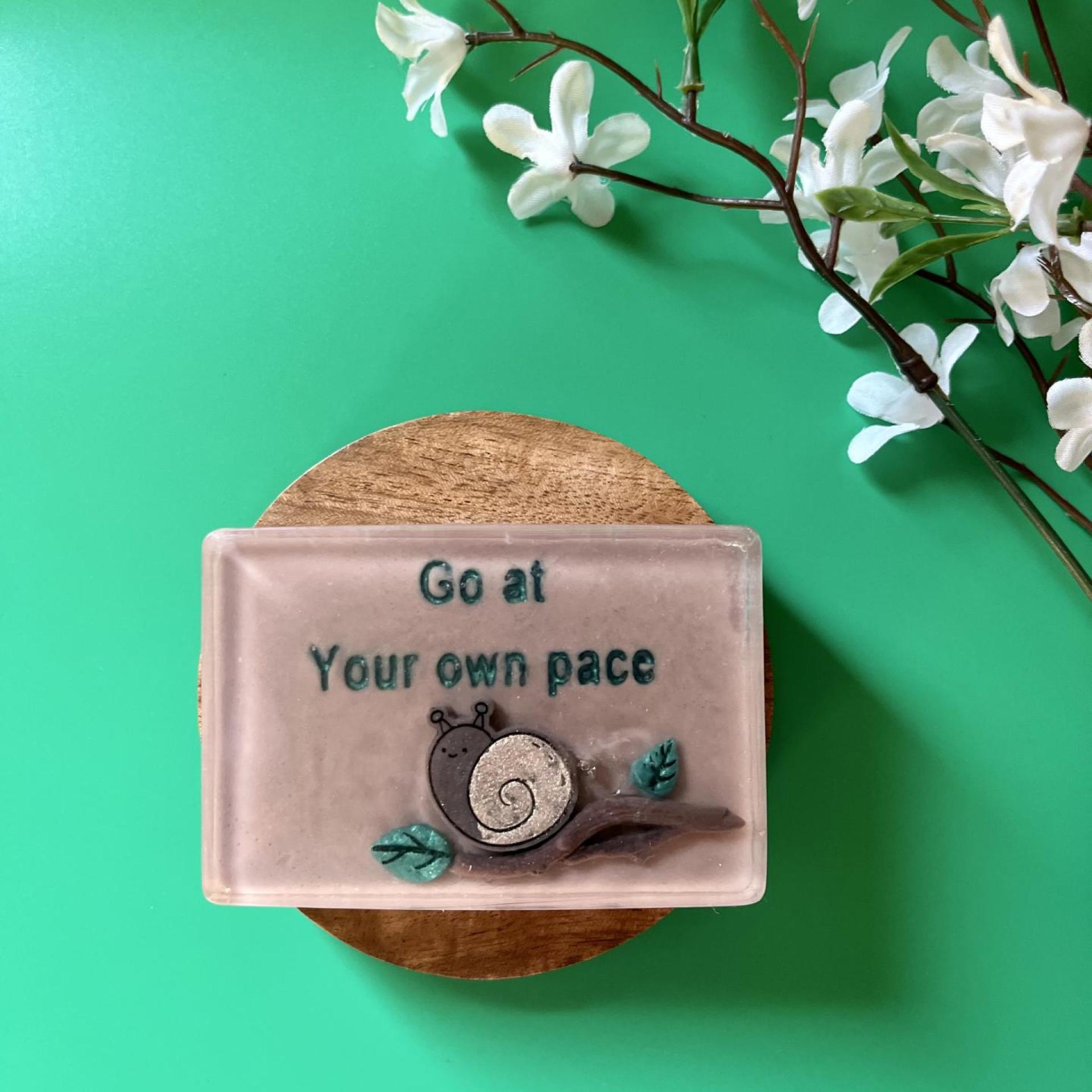 Handmade soap with cute kawaii snail on a branch that reads “go at your own pace”